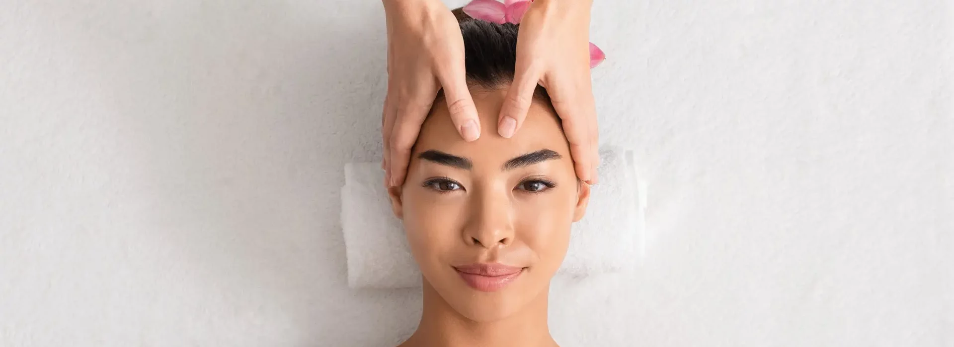 Young asian woman enjoying anti-aging facial massage at spa salon
